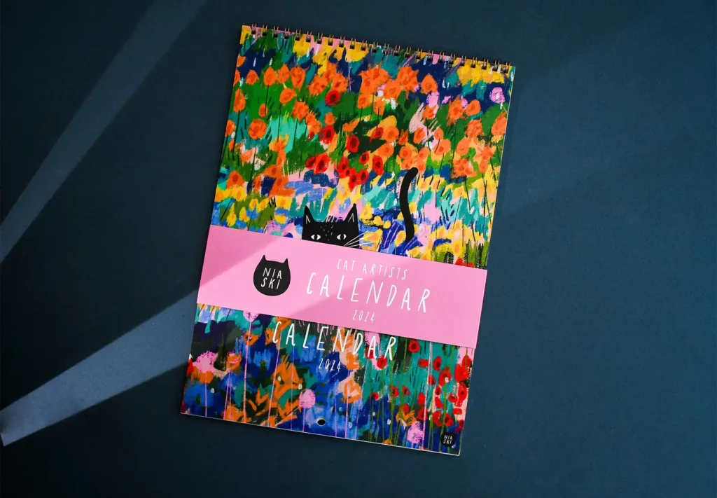 A stunning wall calendar featuring bronze ring binding, complemented by a stylish belly band and adorned with beautiful artwork.