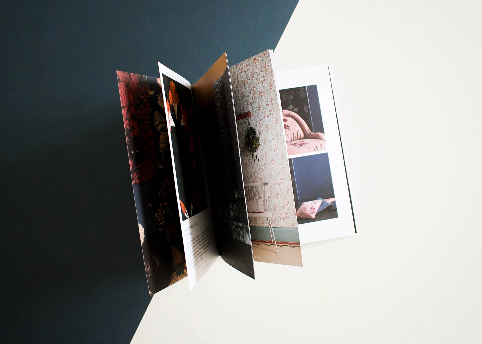 A concertina folded interiors brochure standing open, its panels fanned to show wallpaper and room photography.