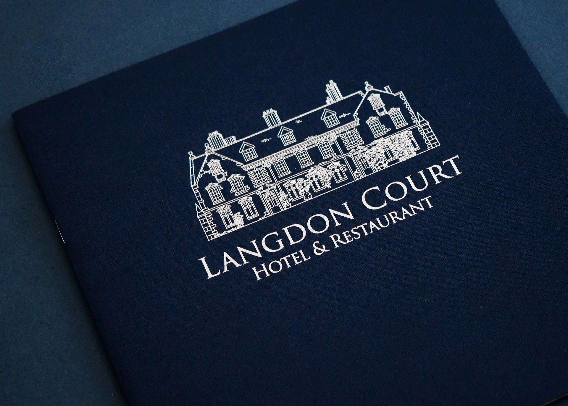 Langdon Court Hotel and Restaurant brochure cover, silver foil line drawing of the house on navy.
