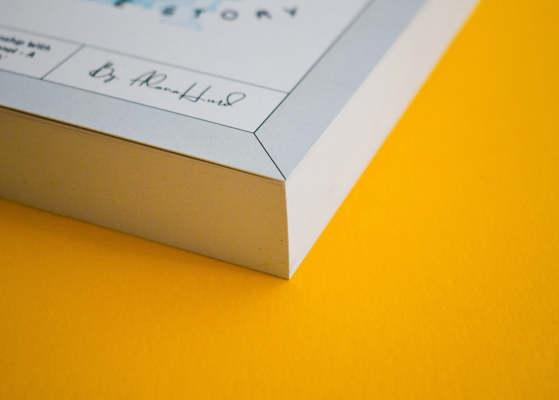 Corner of a perfect bound book, cream text pages visible along the square fore-edge.