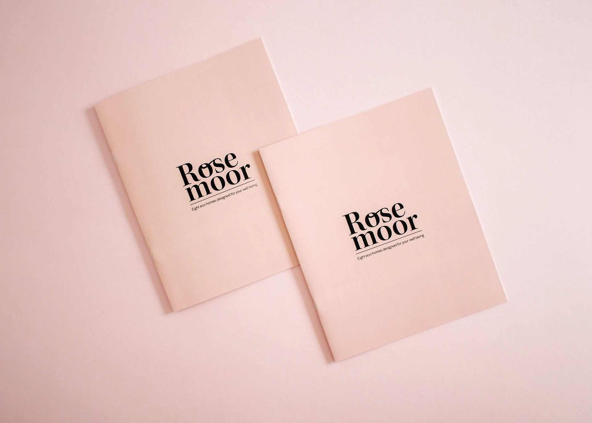 Two brochures with black logos on pale pink uncoated stock, shown flat.