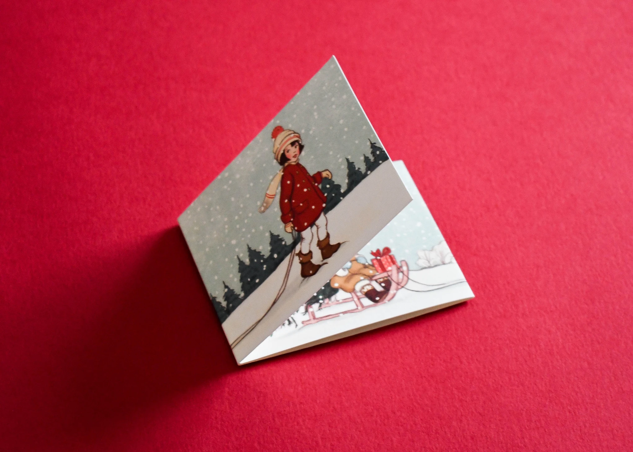 Christmas card with a vintage sledging illustration, standing partly open.