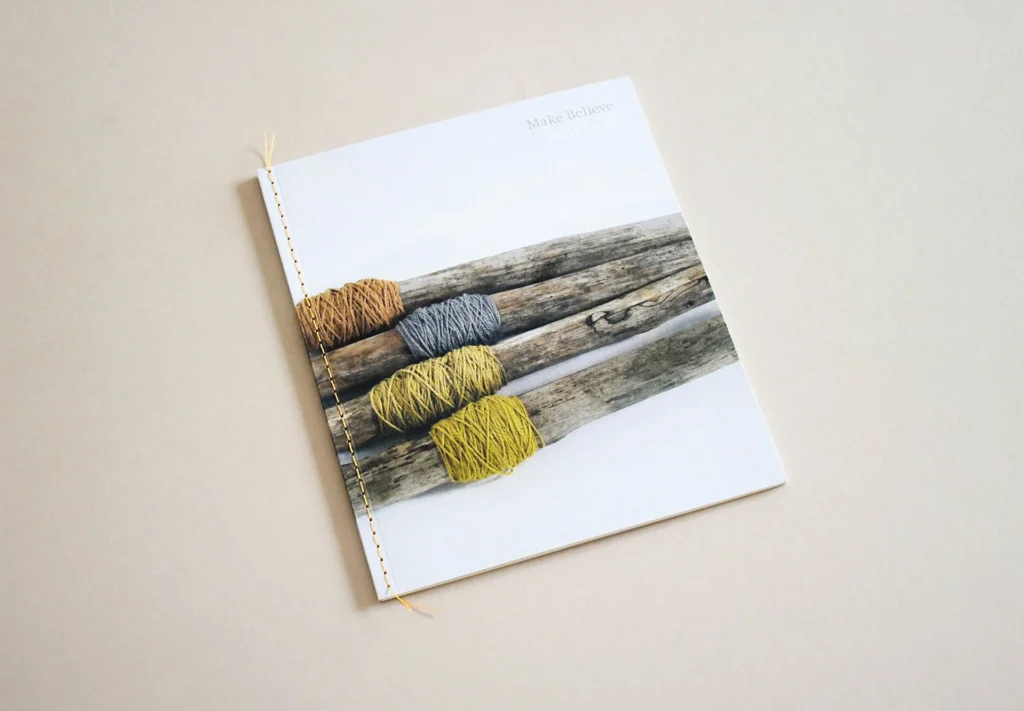 A custom-printed brochure featuring a bookmark ribbon and bespoke yellow stitching on the spine, adding a unique and elegant touch to its design.