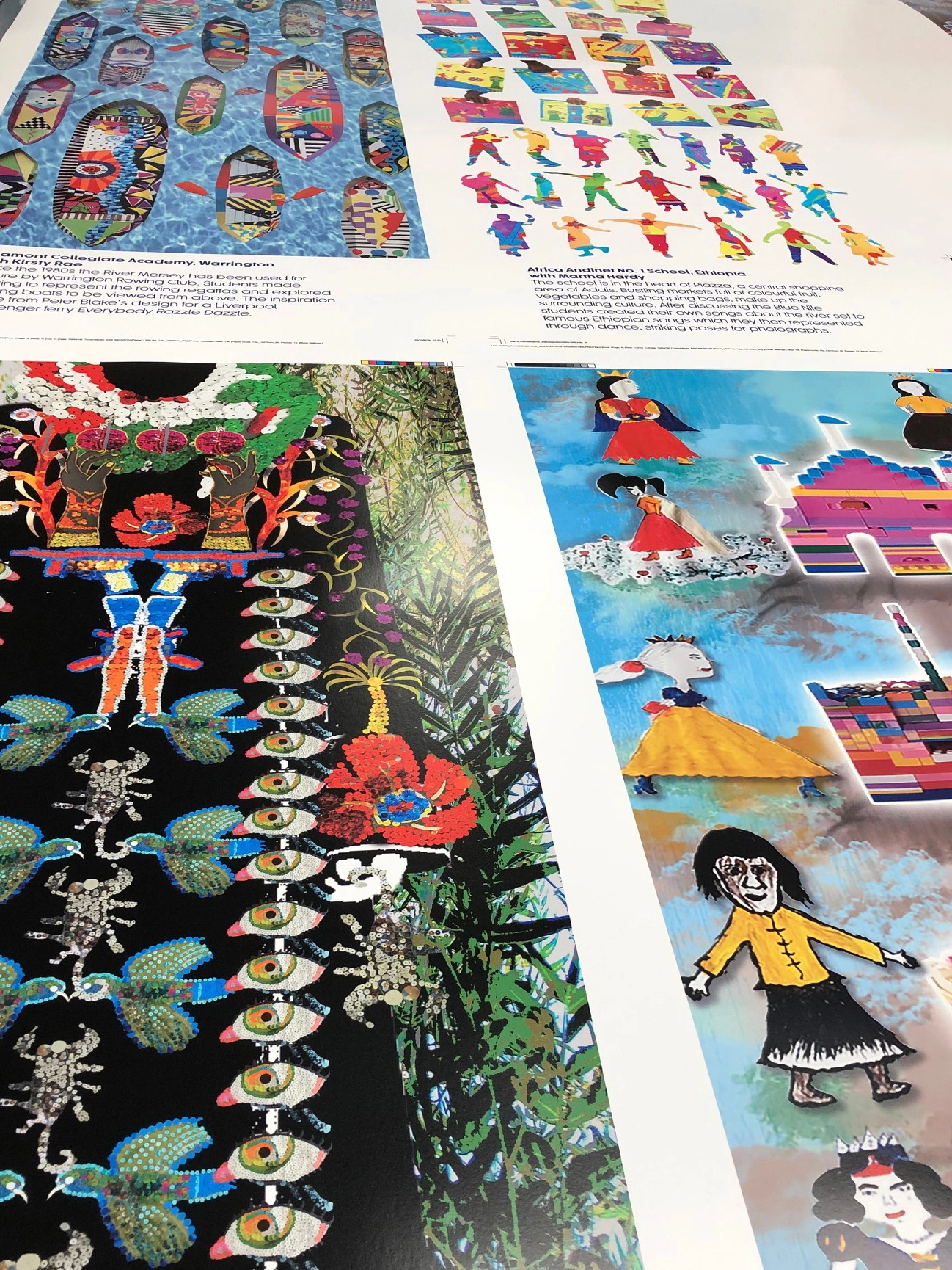 High-angle view of large printed proof sheets featuring various colourful illustrated artwork panels and educational story descriptions.