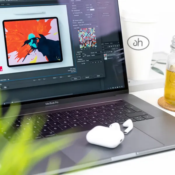 A graphic designers desk with laptop and headphones.