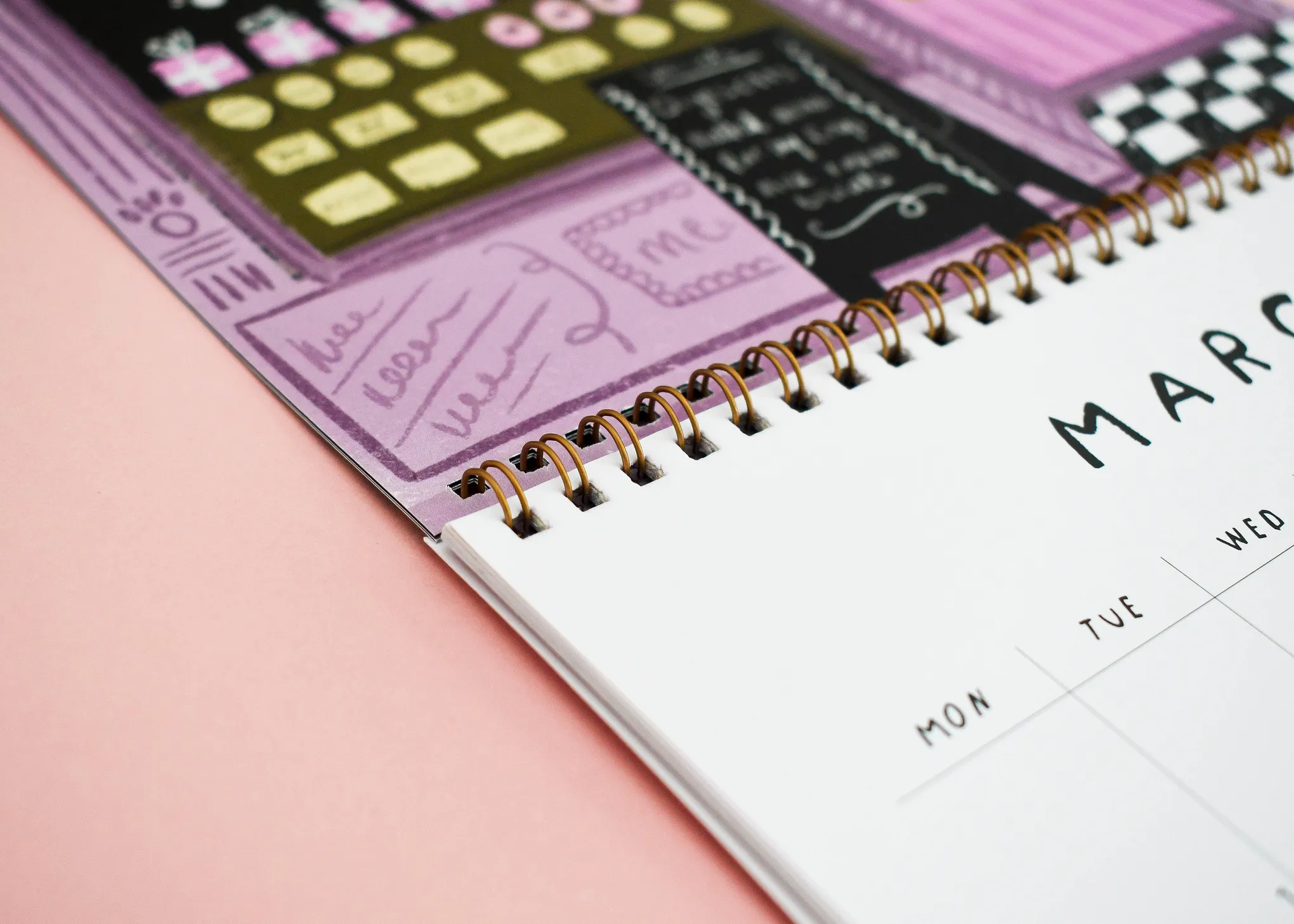Wire bound calendar with full colour monthly artwork laid flat on a worktop.