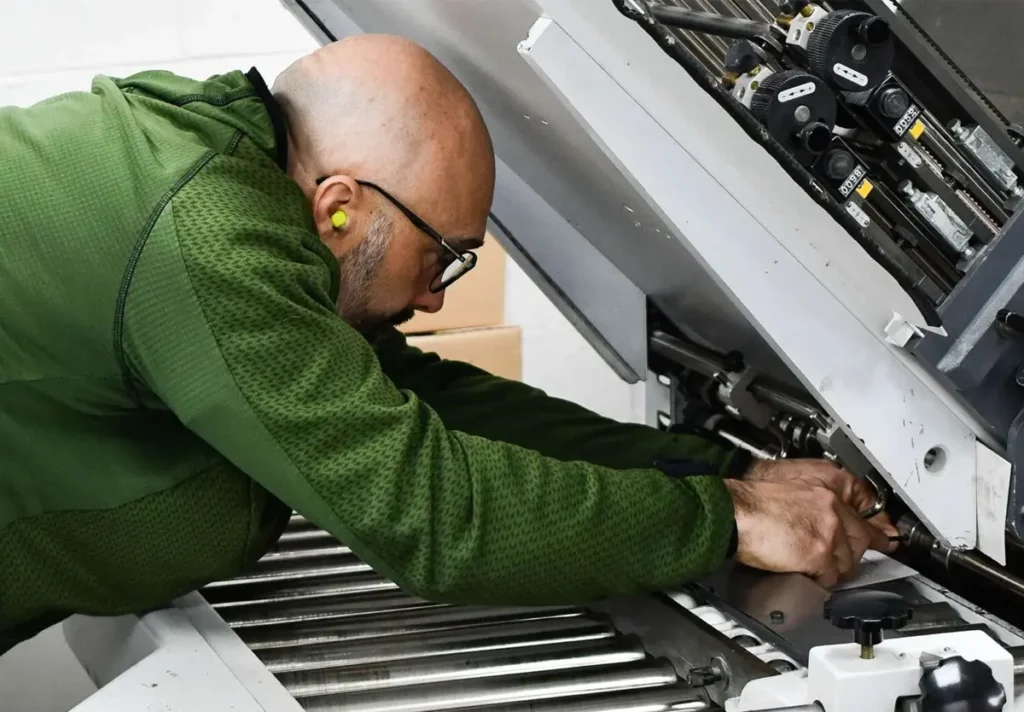 Staff member setting up machinery for a magazine print run.