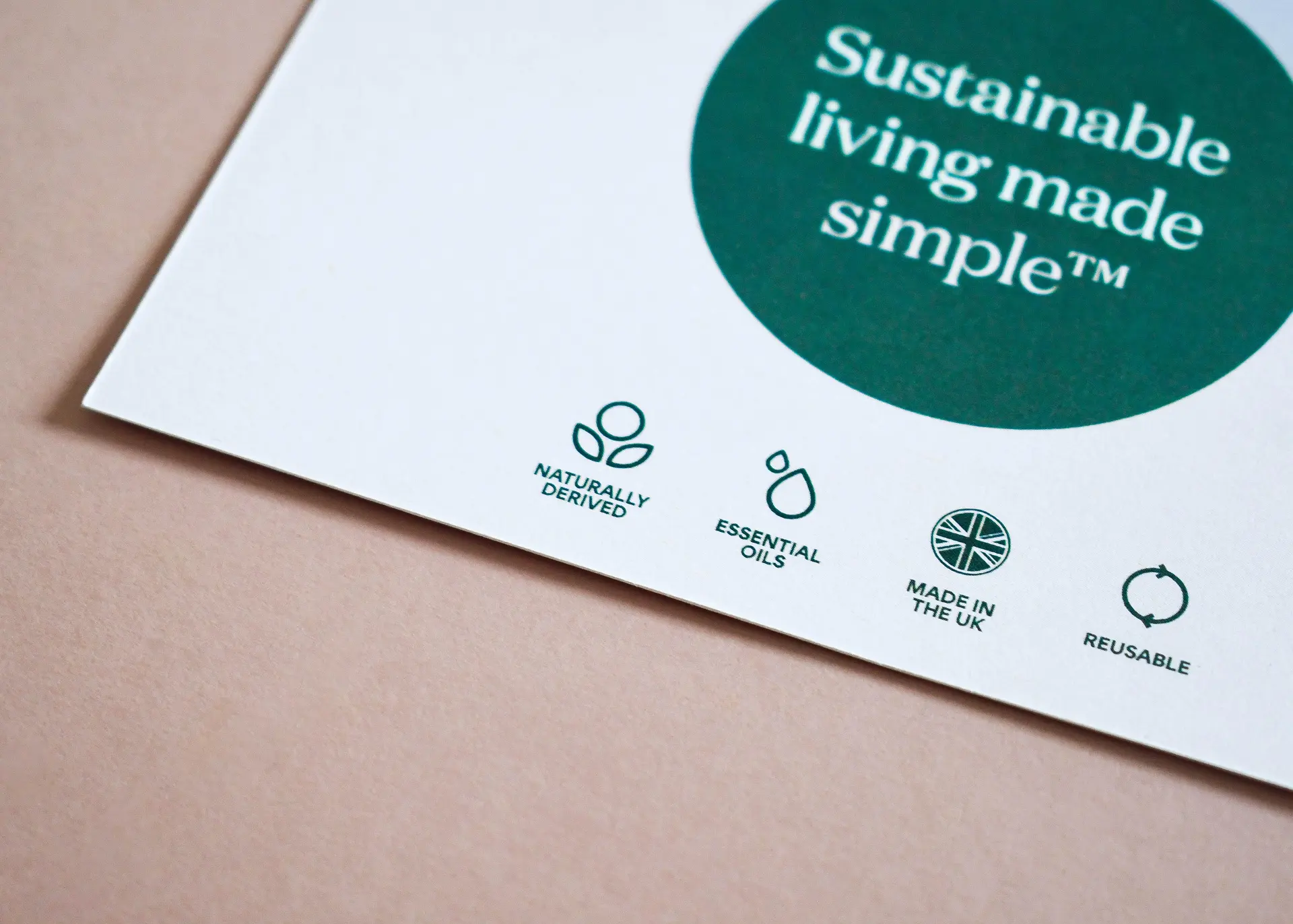 Close-up of sustainable printed packaging featuring eco-friendly icons including naturally derived ingredients, essential oils, made in the UK and reusable messaging.