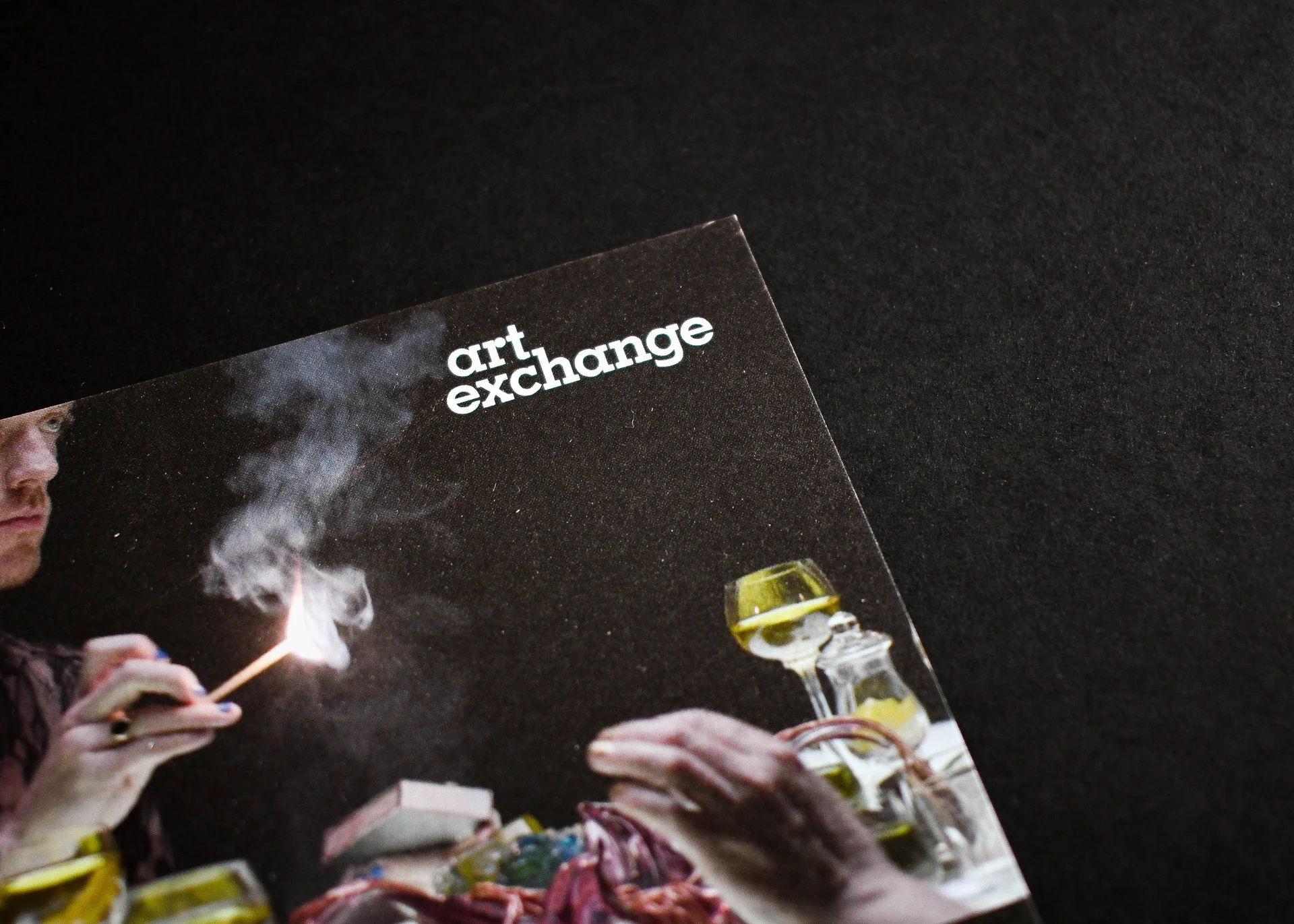 Close-up of a dark promotional flyer for an art exhibition and dining event