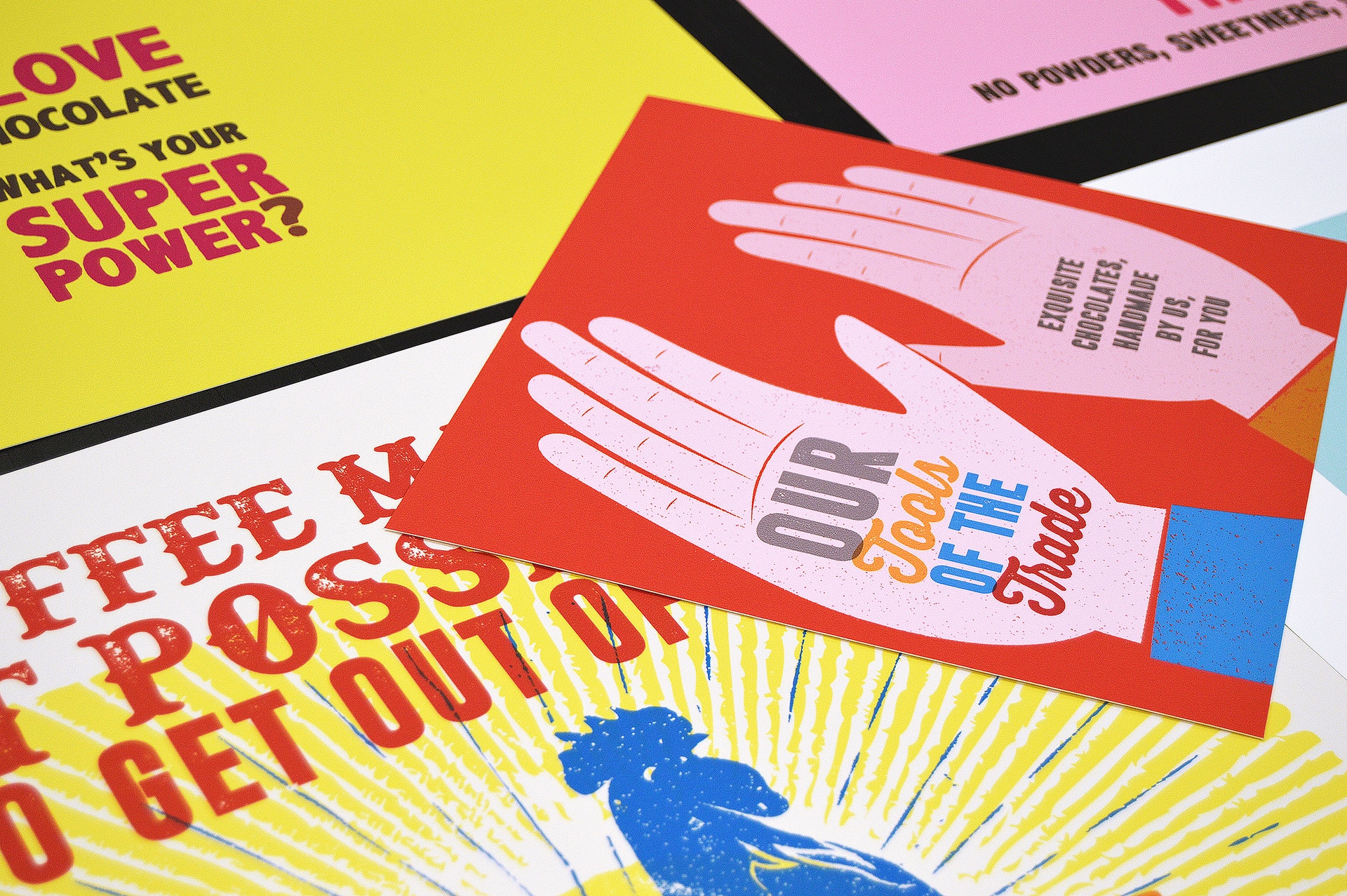 Collection of brightly coloured posters featuring bold lettering, illustrated hands and playful graphic layouts