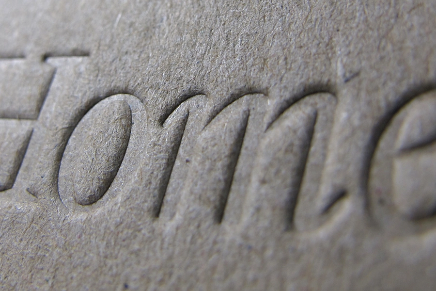 Close-up of embossed lettering pressed into textured grey paper