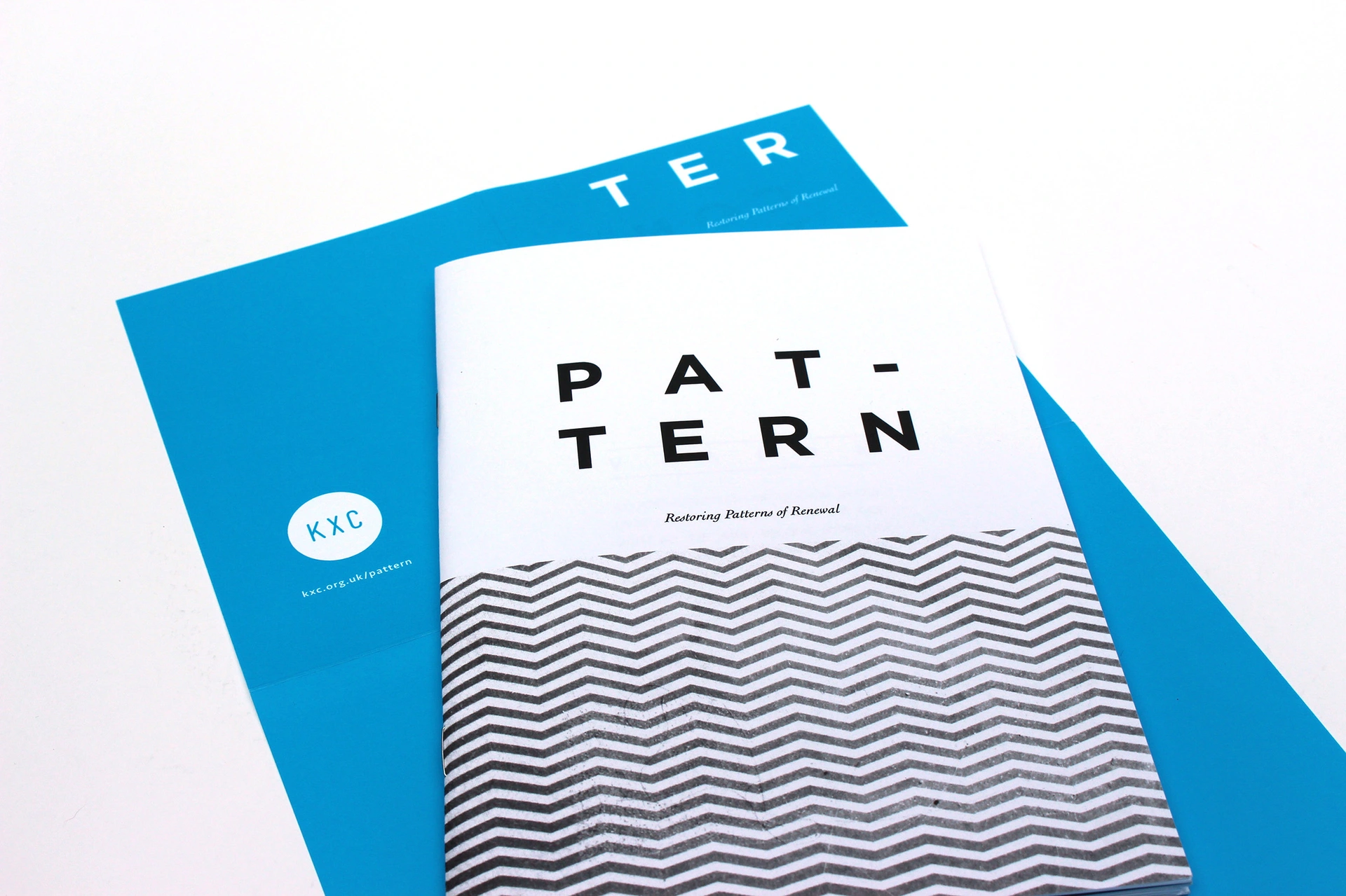 Printed publication featuring bold black typography, monochrome zigzag patterns and a bright blue cover