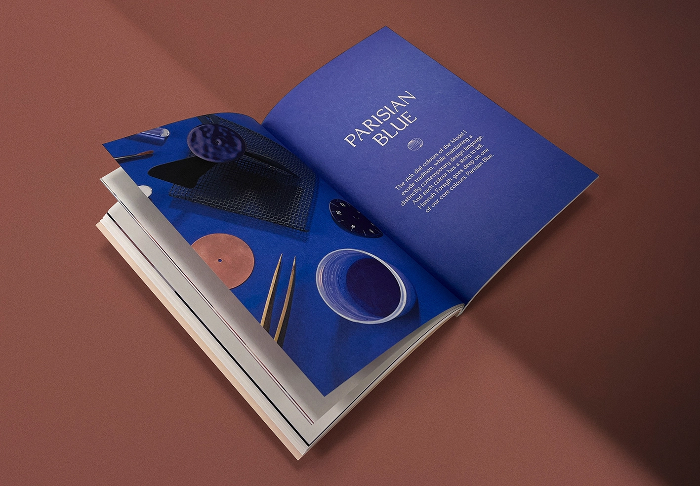 Open premium magazine displaying a deep blue editorial spread with product styling and refined typography