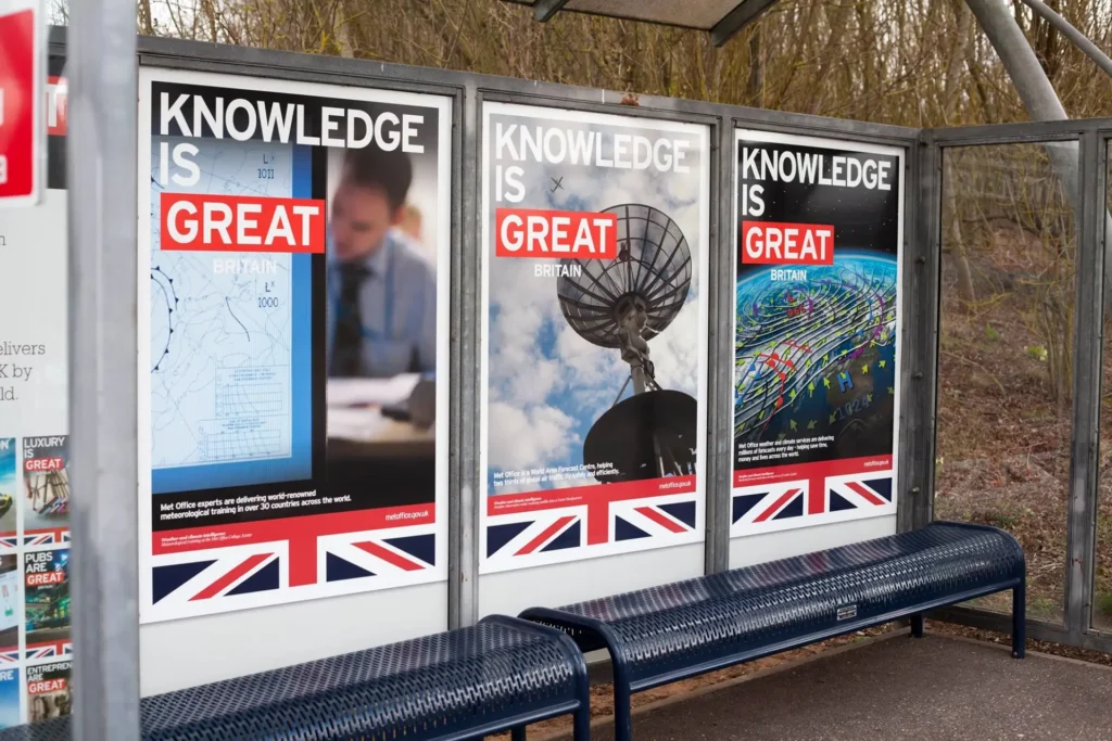 Three large outdoor posters displayed side by side in a roadside bus shelter.