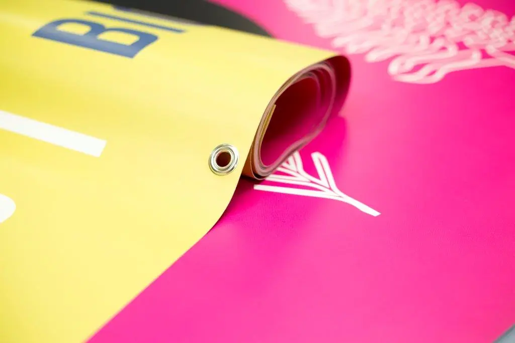 Corner of a rolled PVC banner, showing the metal eyelet used to fix it.