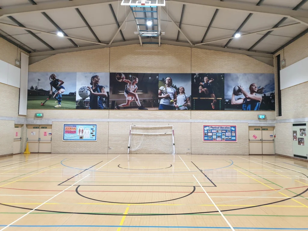 Sports hall with a long printed wall graphic of players mounted above the court.