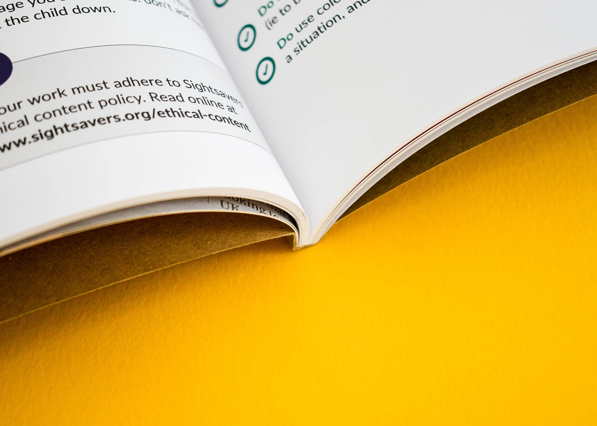 Close-up shot of an open PUR-bound booklet against a yellow background, showing the inner spine joint and crisp text pages.