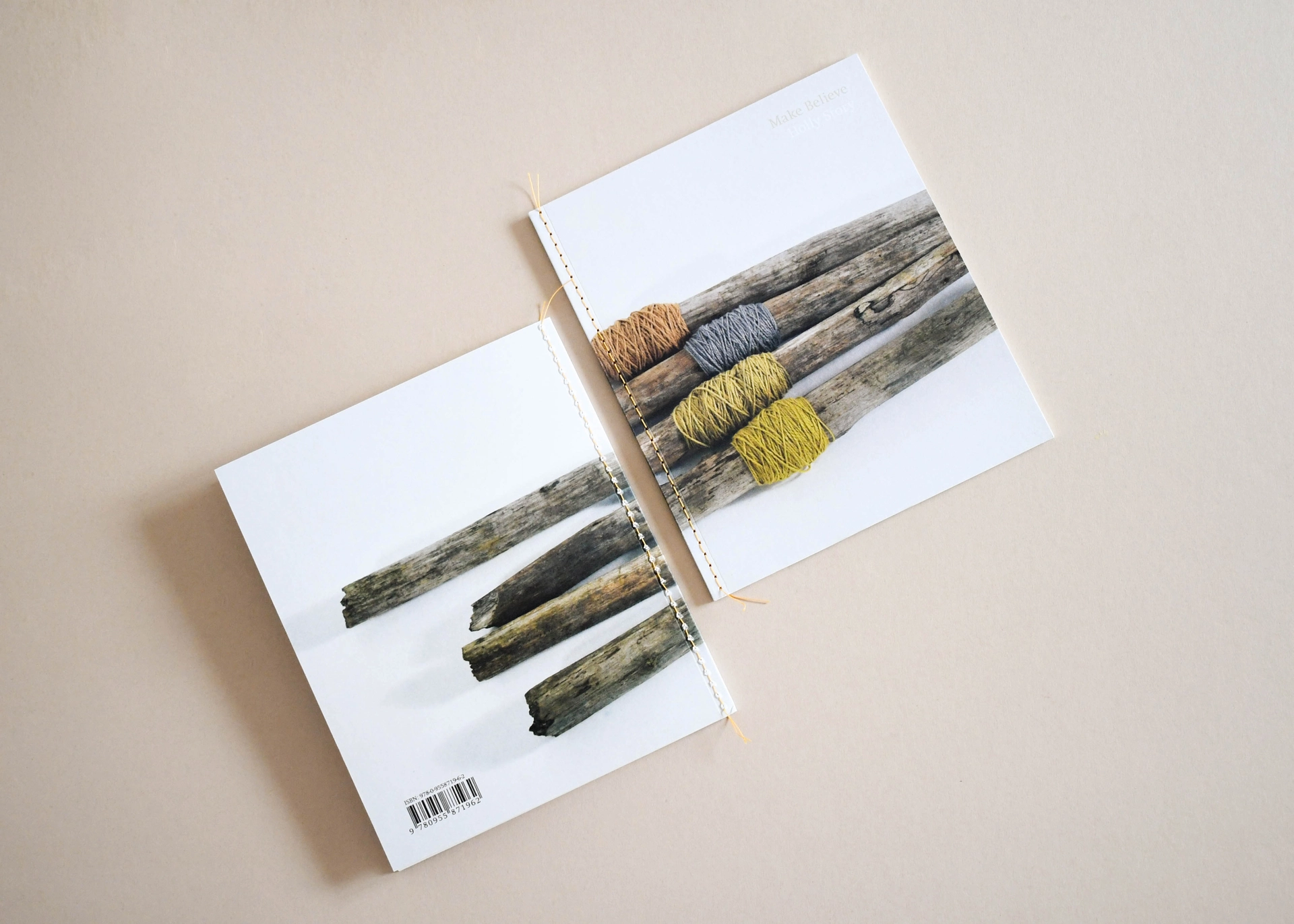 Top-down view of two custom Singer-stitched booklets with exposed yellow thread sewn down the spine, displayed flat on a neutral background