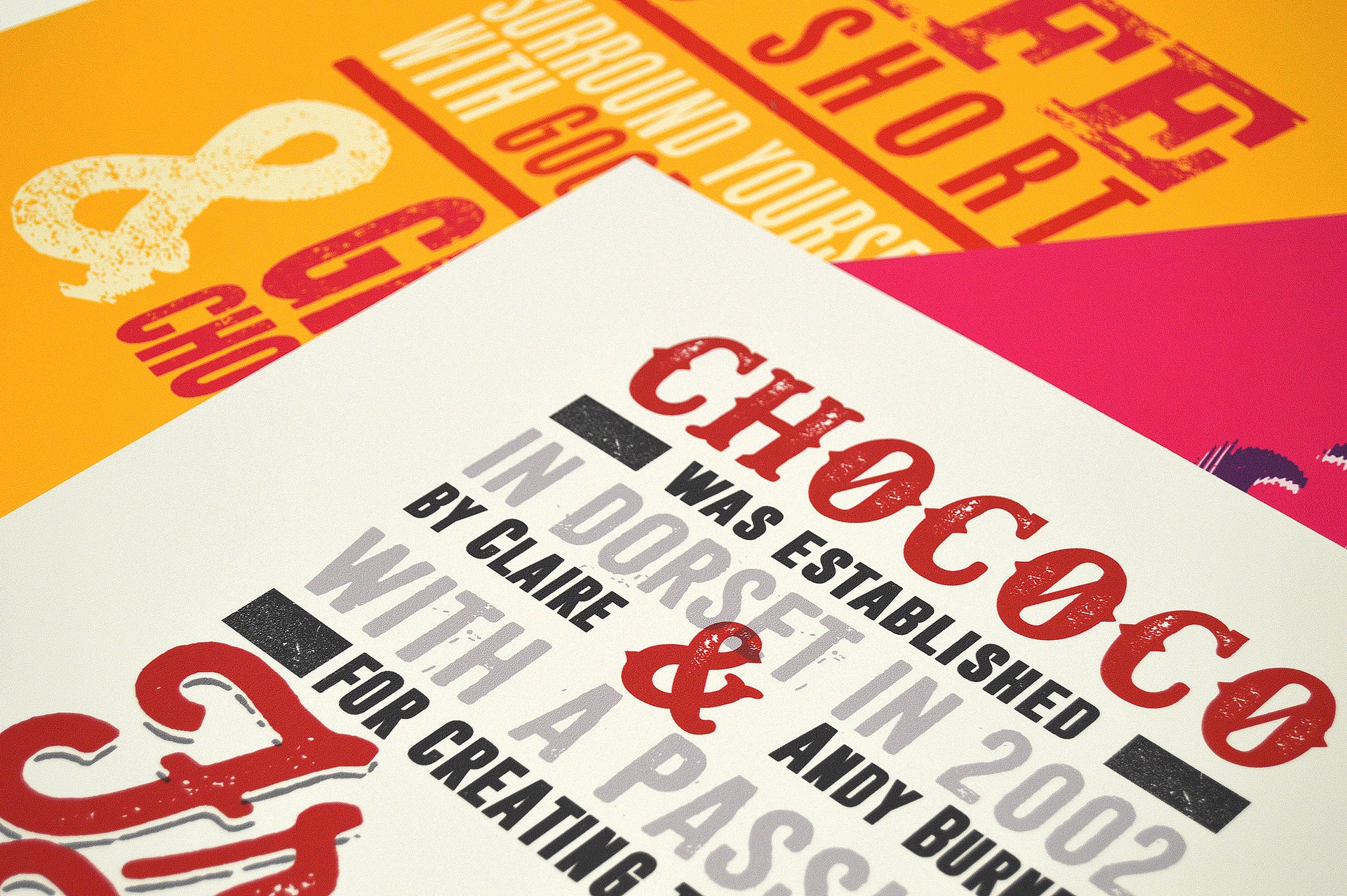 Close-up angled detail of eco-friendly printed cardstock with red and black letterpress typography for a sustainable corporate chocolate brand.